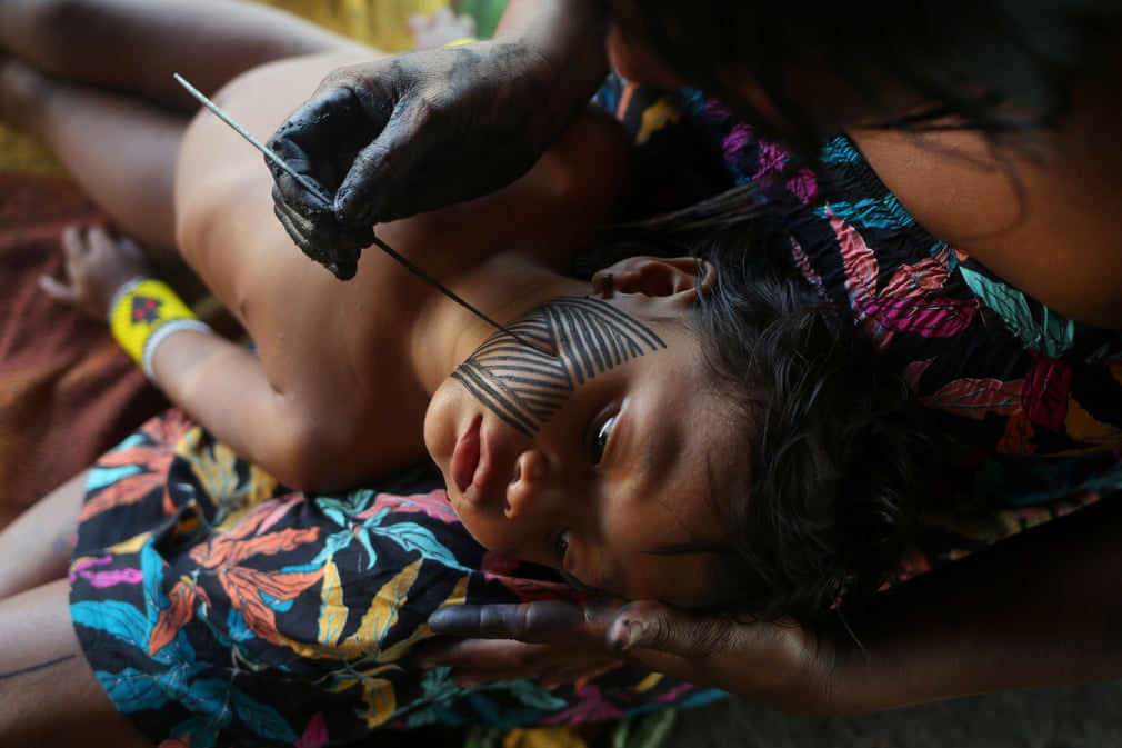 عکس روز/ یک بومی برزیل در حال رنگ آمیزی صورت فرزندش