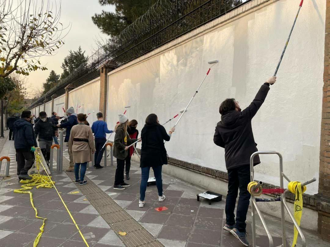 سفیر انگلیس در تهران در حال پاک کردن شعار‌ها از روی دیوار