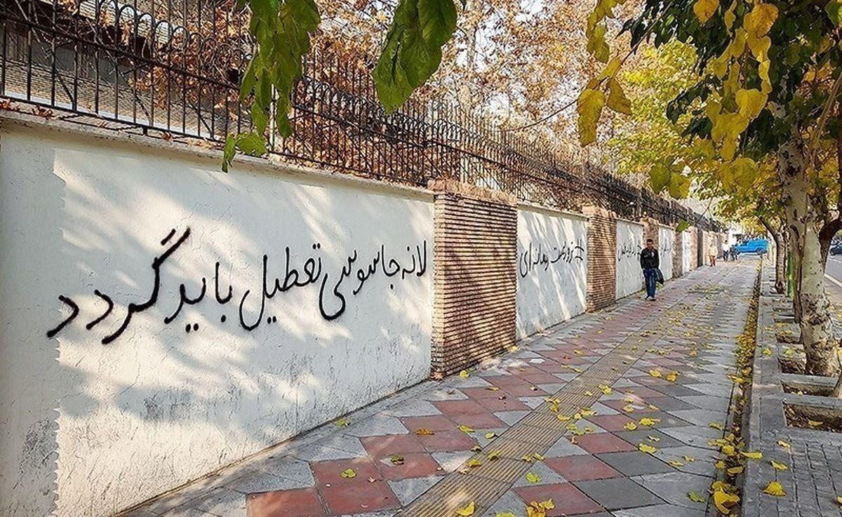سفیر انگلیس در تهران در حال پاک کردن شعار‌ها از روی دیوار