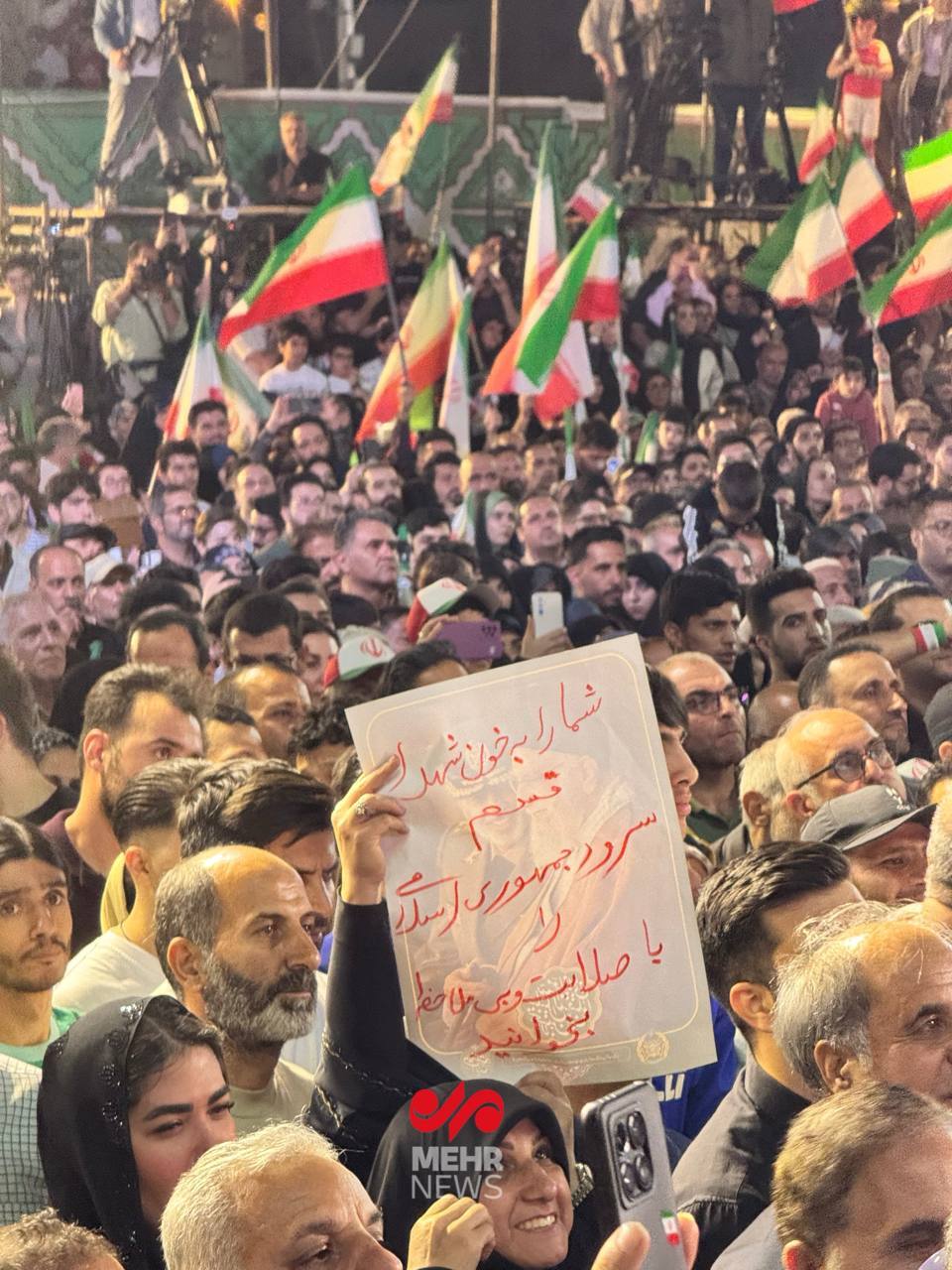 پلاکاردی در دست مردم حاضر در میدان انقلاب خطاب به تیم ملی