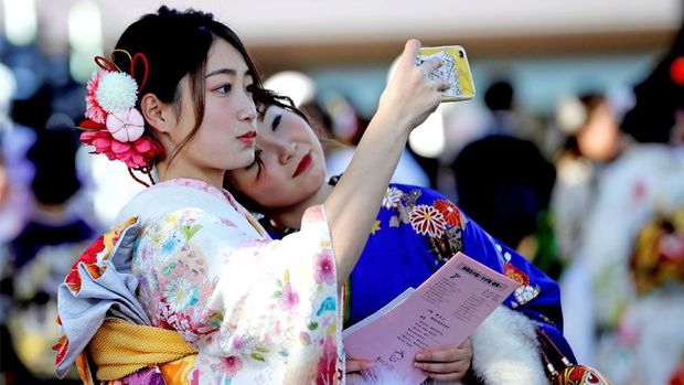 دو دختر با لباس‌های کیمونو در حال گرفتن عکس سلفی در پارک تفریحی 