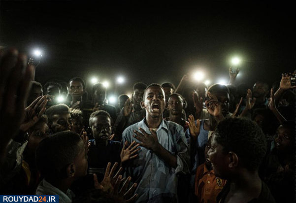 جوانی که دراعتراض به قانون شهروندی در سودان برخلاف در میان معترضانی که شعار می‌دهند شعری را با آواز می‌خواند